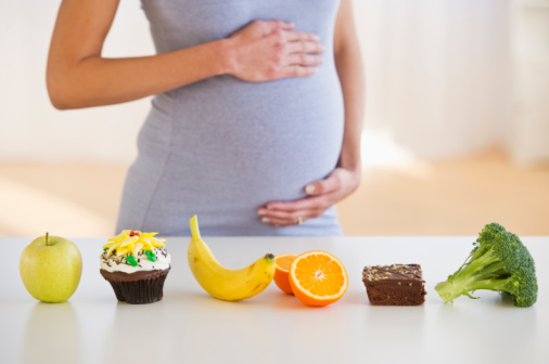 Pregnant woman standing behind a row of food