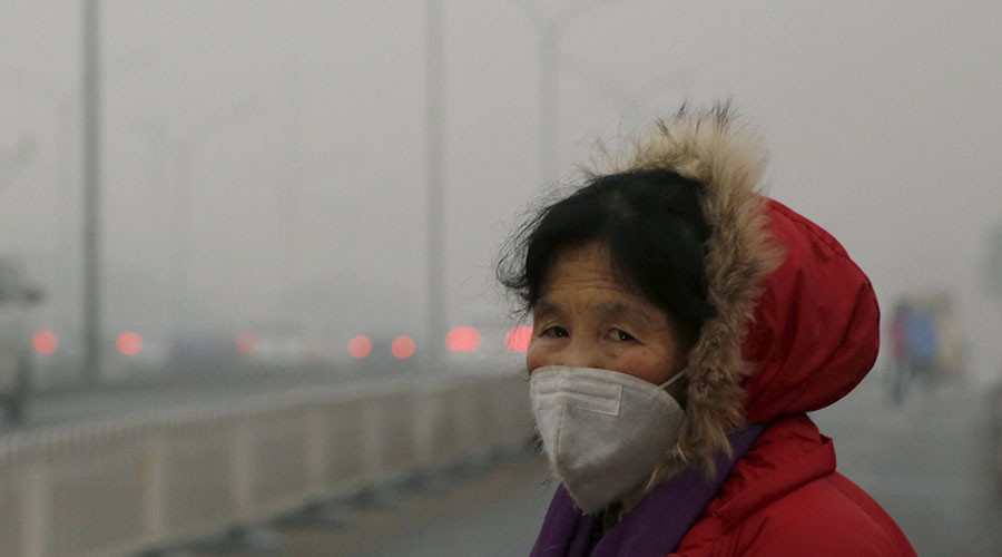 A woman wearing a protective mask makes her way on an extremely polluted day as hazardous, choking smog continues to blanket Beijing