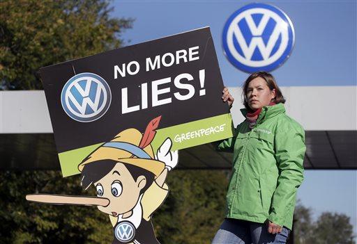 An activist of the environmental protection organization 'Greenpeace' holds a protest poster in front of a factory gate of the German car manufacturer Volkswagen in Wolfsburg, Germany, Friday, Sept. 25, 2015, where the supervisory board meet to discuss who to name as CEO after Martin Winterkorn quit the job this week over an emissions-rigging scandal that's rocking the world's top-selling automaker. (AP Photo/Michael Sohn)