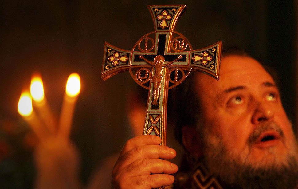 epa02519495 A Greek Orthodox priest holds up a cross during Christmas services at a Greek Orthodox church in Gaza City, in the Gaza Strip, 07 January 2011. Christmas falls on 07 January for Orthodox Christians in Eastern Orthodox churches that use the Julian calendar instead of the 16th-century Gregorian calendar adopted by Catholics and Protestants and commonly used in secular life around the world. EPA/ALI ALI