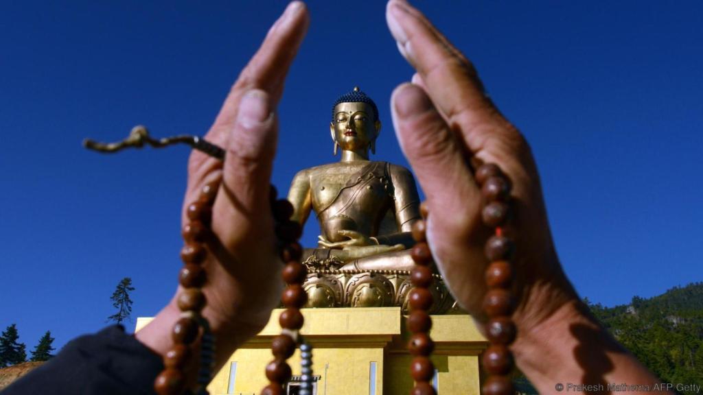 A Bhutanese Buddhist devotee poses for a photograph as he offers prayers at the Buddha Dordenma statue in Thimphu on October 23, 2014. Bhutan -- nestled in the Himalayas and flanked by both India and China -- is renowned for its rich Buddhist culture, and villages are still steeped in its traditions. Protecting the Buddhist culture is a key pillar of Bhutan's unique "Gross National Happiness" development model, which aims to balance spiritual and mental well-being with economic growth. AFP PHOTO/Prakash MATHEMA        (Photo credit should read PRAKASH MATHEMA/AFP/Getty Images)