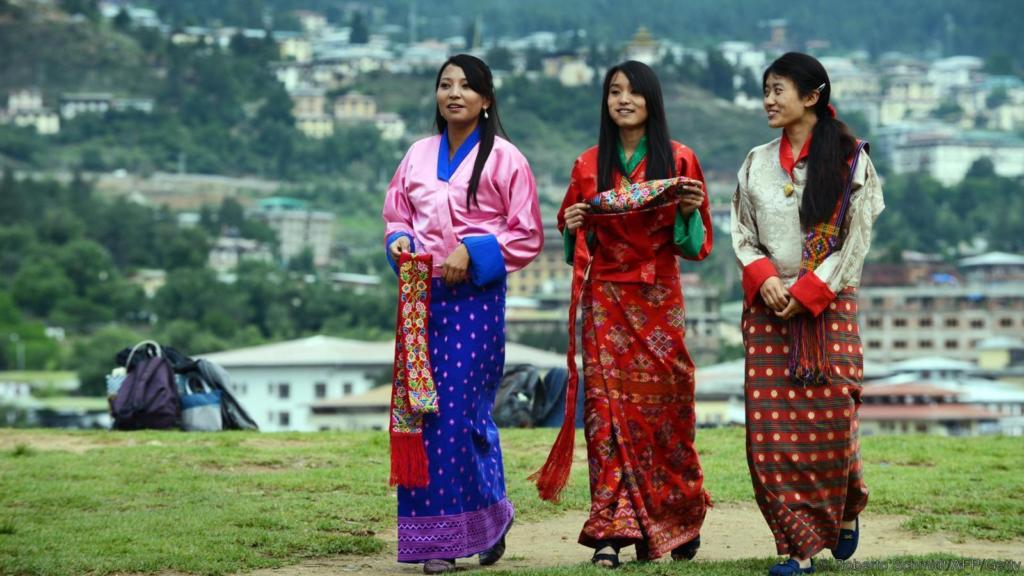 TO GO WITH Bhutan-politics-economy-health-labour-social-youth,FEATURE by Rachel O'BRIEN Schoolgirls wear traditional Bhutanese dresses before a cultural event to celebrate the birth date of Bhutan's fourth king at a local school in Thimphu on June 2, 2013.   It is known as "the last Shangri-La" -- a remote Himalayan nation, rich in natural beauty and Buddhist culture, where national happiness is prioritised over economic growth. But urban youngsters in the kingdom of Bhutan are quick to challenge its rosy reputation.  AFP PHOTO/ROBERTO SCHMIDT        (Photo credit should read ROBERTO SCHMIDT/AFP/Getty Images)