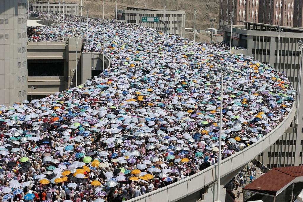 1443082619_muslim-pilgrims-holding-umbrellas-shelter-heat-walk-bridge-they-head-mina-cast-stones[1]